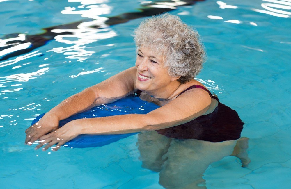 Atividade motora para idosos. Foto de uma senhora idosa na piscina praticando natação.