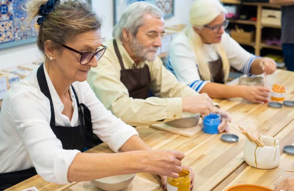 Foto de Idosos sentados usando tinta para uma pintura.