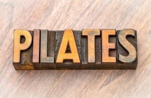 Pilates. Na foto tem a palavra pilates escrita em quadradinhos de madeira.
