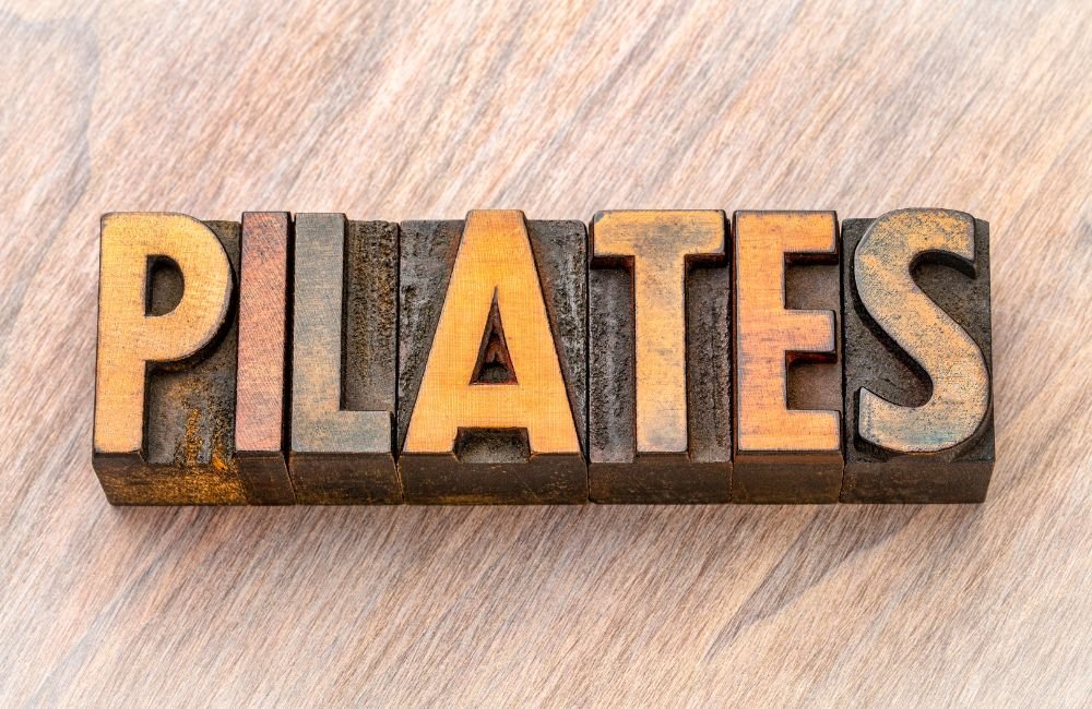 Pilates. Na foto tem a palavra pilates escrita em quadradinhos de madeira.