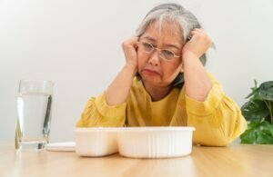 Porque os Idosos Param de Comer? Entenda as Causas e Como Ajudar Foto de uma senhora idosa desanimada em frente ao prato.